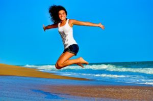 Young woman jumping in the air on the beach